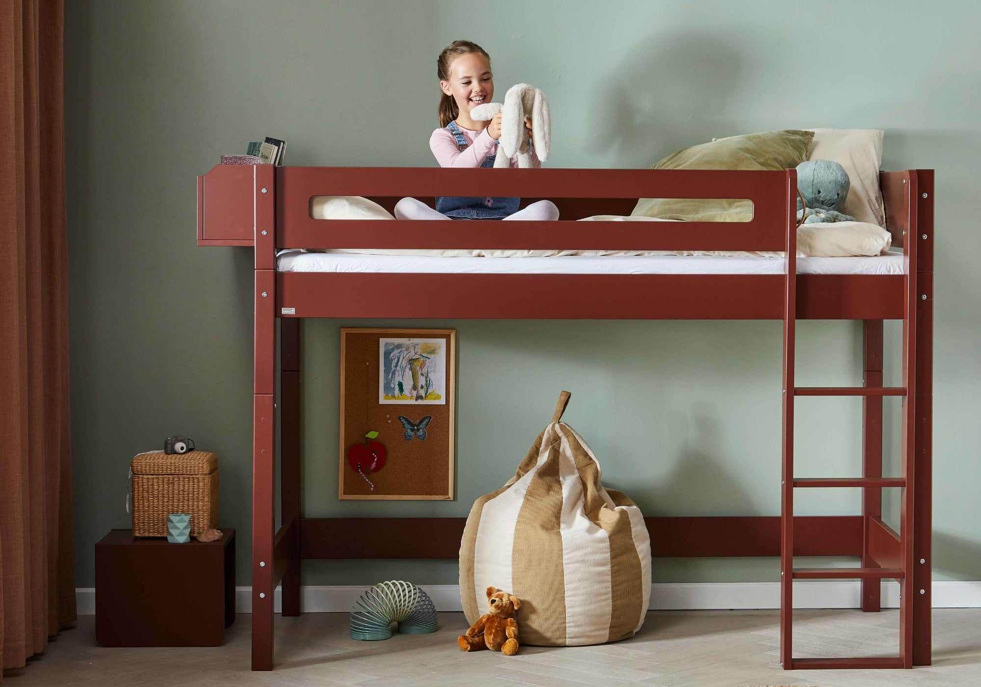 Glad pige leger med bamse i rød Manis-h højseng til børneværelset
