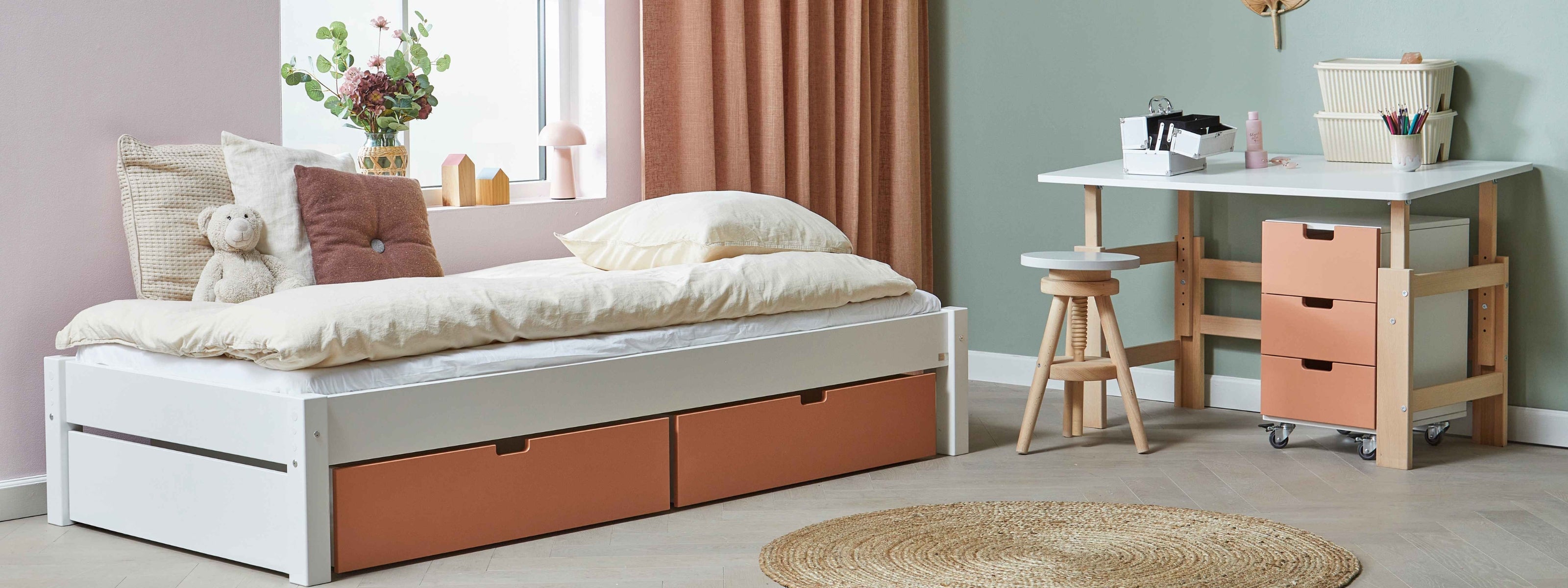 Børneseng med opbevaringsskuffer og justerbart skrivebord i et børneværelse