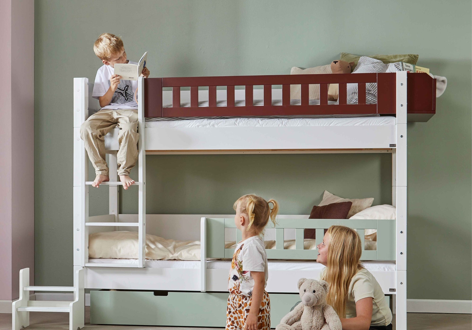 Børn læser og leger ved en køjeseng med opbevaringsskuffer