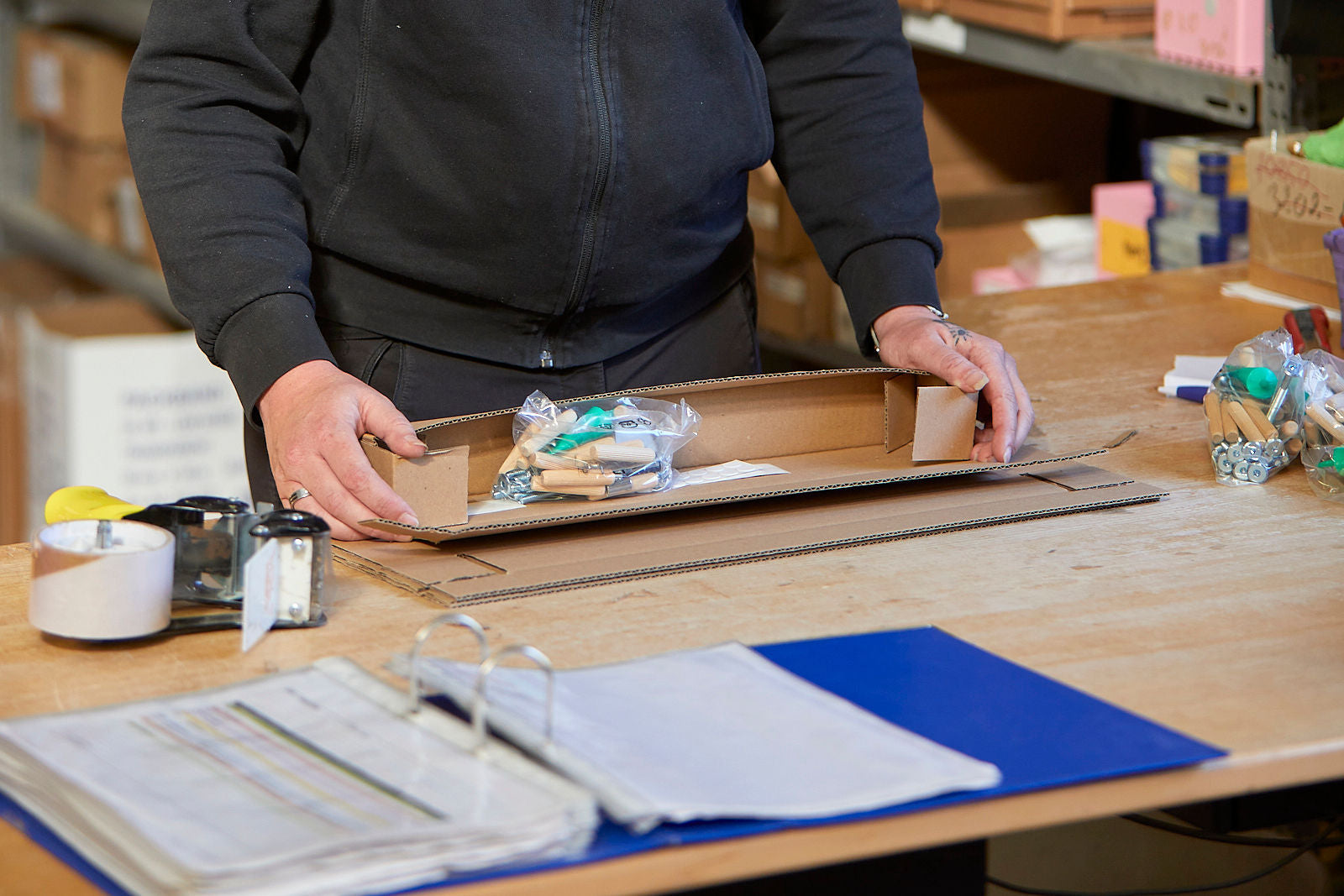 Medarbejder pakker tilbehør til en 3-i-1 stol i en papkasse.