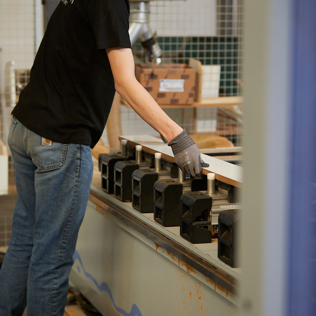 Medarbejder med handsker arbejder med træ på maskine i Manis-h fabrik