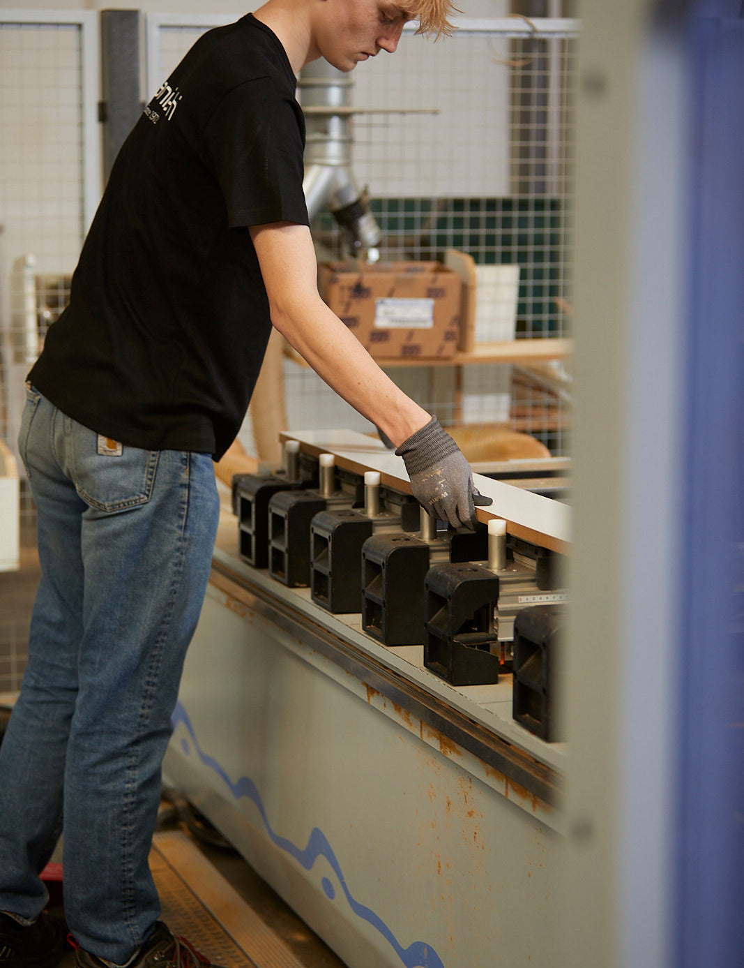 Medarbejder med handsker arbejder med træ på maskine i Manis-h fabrik